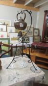 A copper kettle on an ornate wrought iron stand.