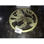 A late 19th century brass trivet depicting a male lion profile and on lion paw feet.