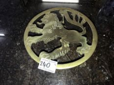 A late 19th century brass trivet depicting a male lion profile and on lion paw feet.