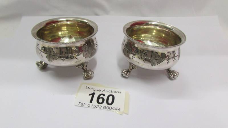 A pair of Victorian silver plate salts with ball and claw feet and decorative design.