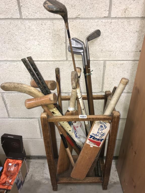 A 1930's oak stitch stand & sports equipment including golf clubs & cricket bats etc.