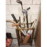 A 1930's oak stitch stand & sports equipment including golf clubs & cricket bats etc.