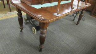 A Victorian mahogany extending dining table with one leaf.