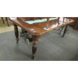 A Victorian mahogany extending dining table with one leaf.