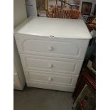 A white three drawer chest.