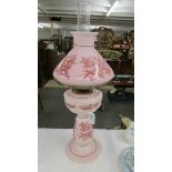 A nice quality pink glass oil lamp hand decorated with birds.