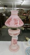 A nice quality pink glass oil lamp hand decorated with birds.