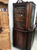 A dark wood stained corner cabinet with astragal glazed door.