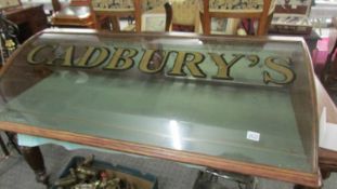 A domed shop display cabinet sign written Cadbury's.