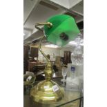 A brass bankers lamp with green glass shade.
