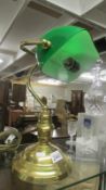 A brass bankers lamp with green glass shade.