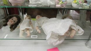 Three porcelain dolls and a porcelain dolls head.
