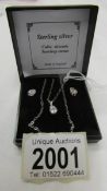 A silver pendant and earring set.