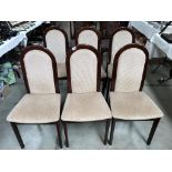 A set of six dark wood stained dining chairs with cream seats.