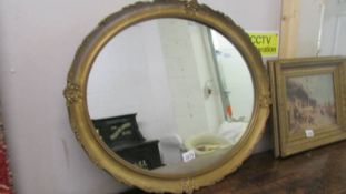 An oval gilt framed mirror.