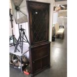 A dark oak corner cupboard with leaded glass door,