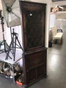 A dark oak corner cupboard with leaded glass door,