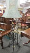 An ornate wrought iron and brass standard lamp with shade.