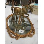 An oval cast mirror and a heavy cast brass horse.