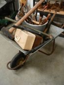 A galvanised wheel barrow with garden tools.