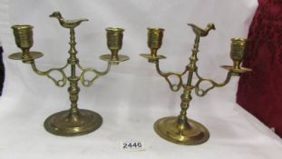 A pair of heavy brass candelabra with birds on top.