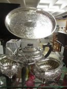An ornate silver plate three piece tea set with oval tray.