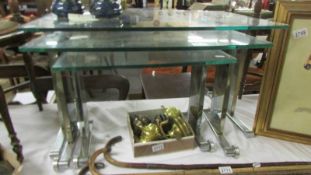 A nest of three retro chrome glass topped tables.