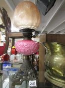 A Victorian oil lamp with pink glass font and original etched shade.