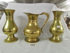 A pair of heavy brass vases and a brass jug.