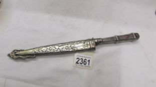 A very ornate white metal knife in sheath.