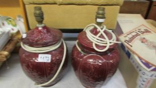 A pair of cherry red pottery urn shaped table lamps