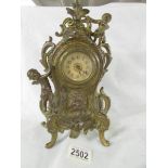 A heavy brass mantel clock surmounted cherubs.