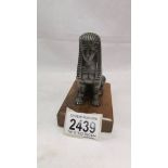 A Sphinx car mascot on wooden base.