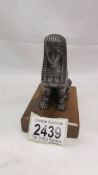 A Sphinx car mascot on wooden base.