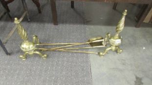 A pair of brass fire dogs together with a set of three brass fire irons.