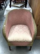 A pink Lloyd loom chair with upholstered seat with storage compartment