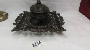 An ornate heavy brass inkwell with glass liner.