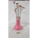A pink hat pin stand with 12 hat pins.