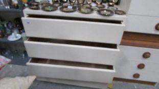 A white three drawer chest.