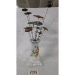 A rose decorated hat pin stand with 14 hat pins.