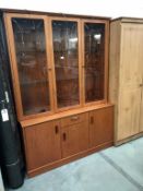 A teak effect wall unit display cabinet (Base 130cm x 42cm x 69cm high,)(Top 130cm x 30cm x 116.