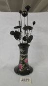 A bird decorated hat pin stand with 15 hat pins.