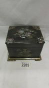 A late Victorian black lacquer tea caddy inlaid with mother of pearl.