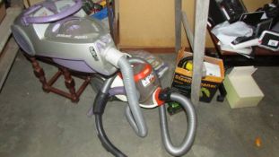 A Vax vacuum cleaner, a Black and Decker vacuum and a hand steam cleaner.