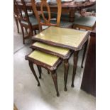 A glazed top nest of dark wood stained tables with green leather inserts (55cm x 42cm x 56cm high)