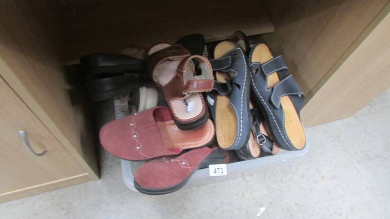 A box of assorted sandals and shoes.