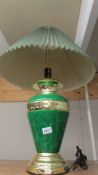 A green and gilded table lamp with shade.