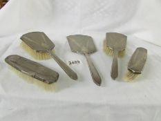 A silver backed vanity set comprising hand mirror, 2 hair brushes and 2 other brushes,