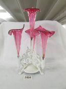 A metal based epergne with cranberry glass trumpets.