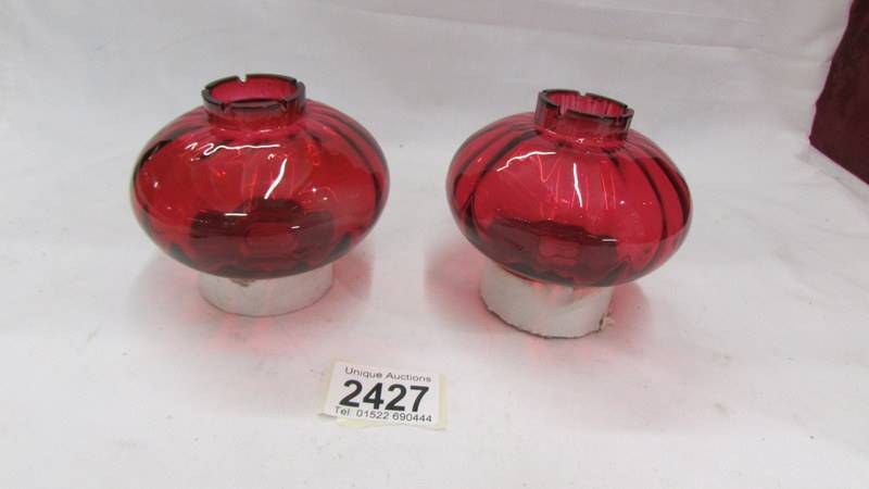 A pair of cranberry glass oil lamp peg fonts.